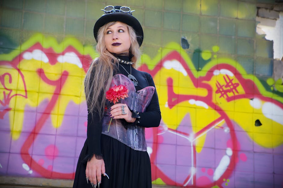 Stylish woman in gothic attire posing against a vibrant graffiti wall.