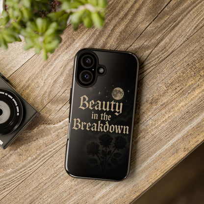 Phone case with 'Beauty in the Breakdown' text on a wooden surface with a camera and plant.