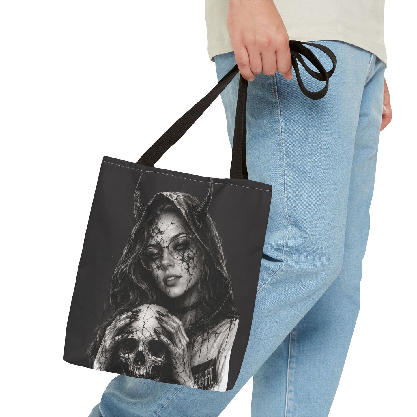 Person holding a tote bag with a black and white design of a woman and skull.