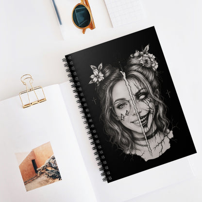 Spiral-bound notebook with a black and white illustration of a woman's face on a white surface.