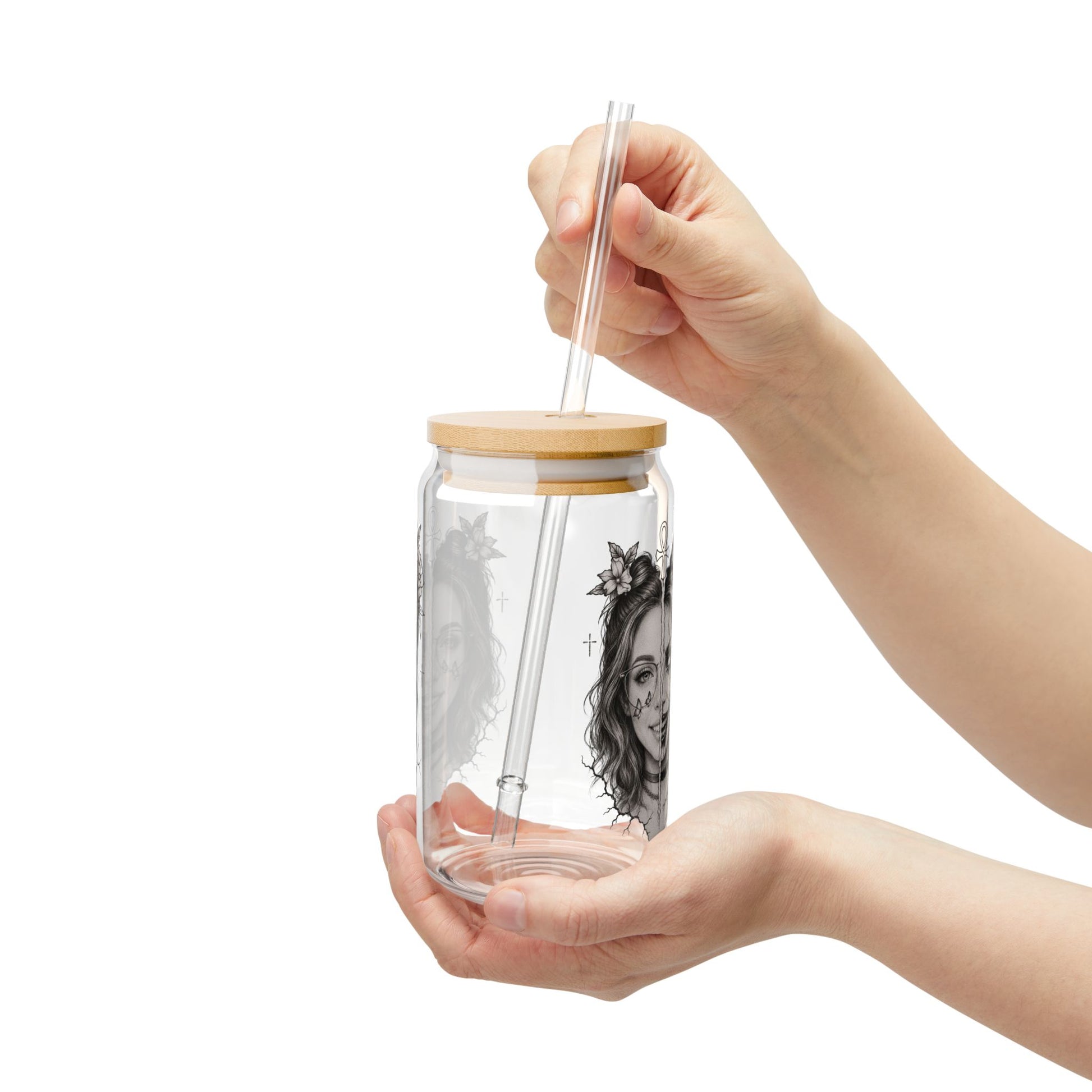 Glass jar with wooden lid and straw held by a hand on a white background